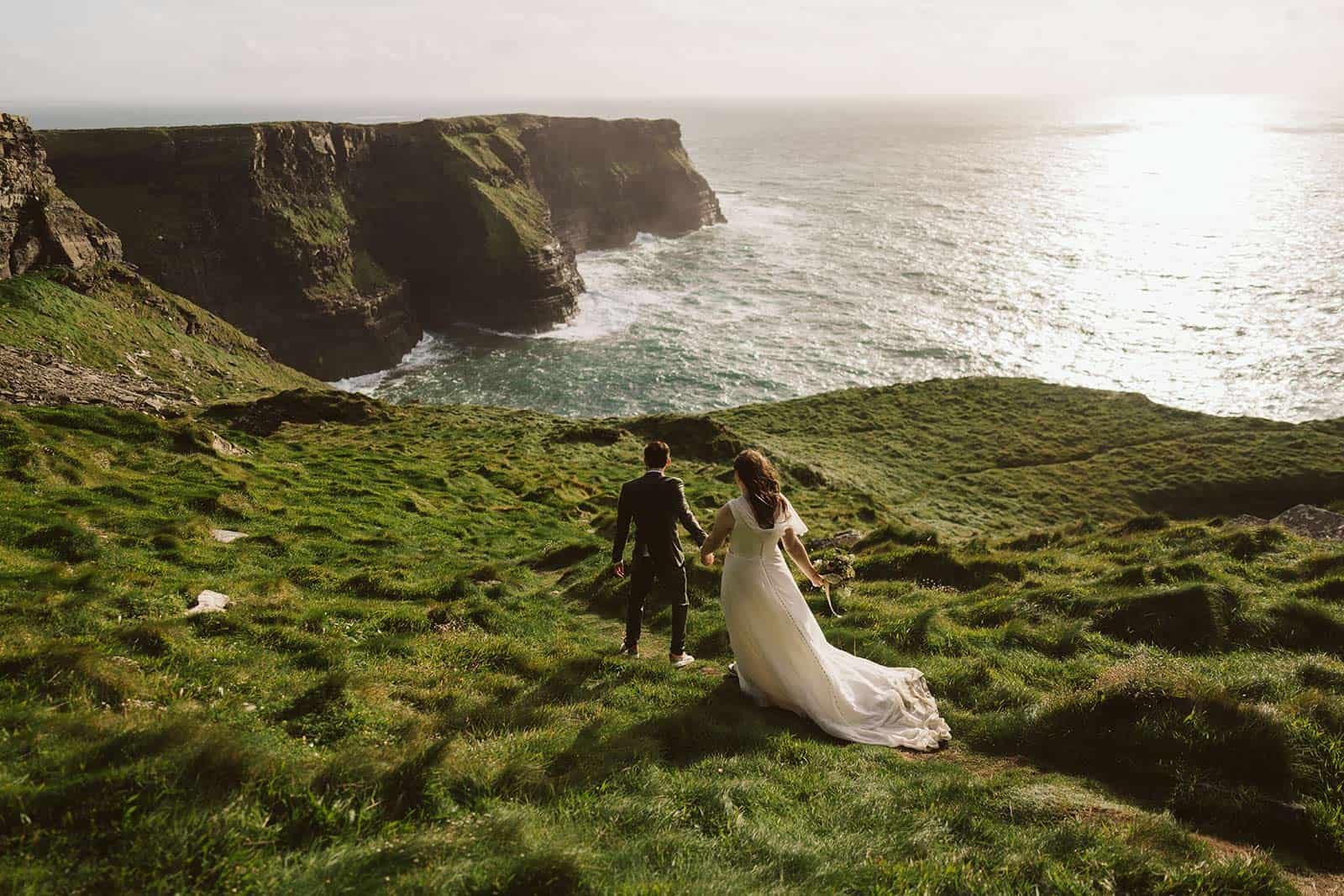 couple walk on the cliffs while eloping in ireland