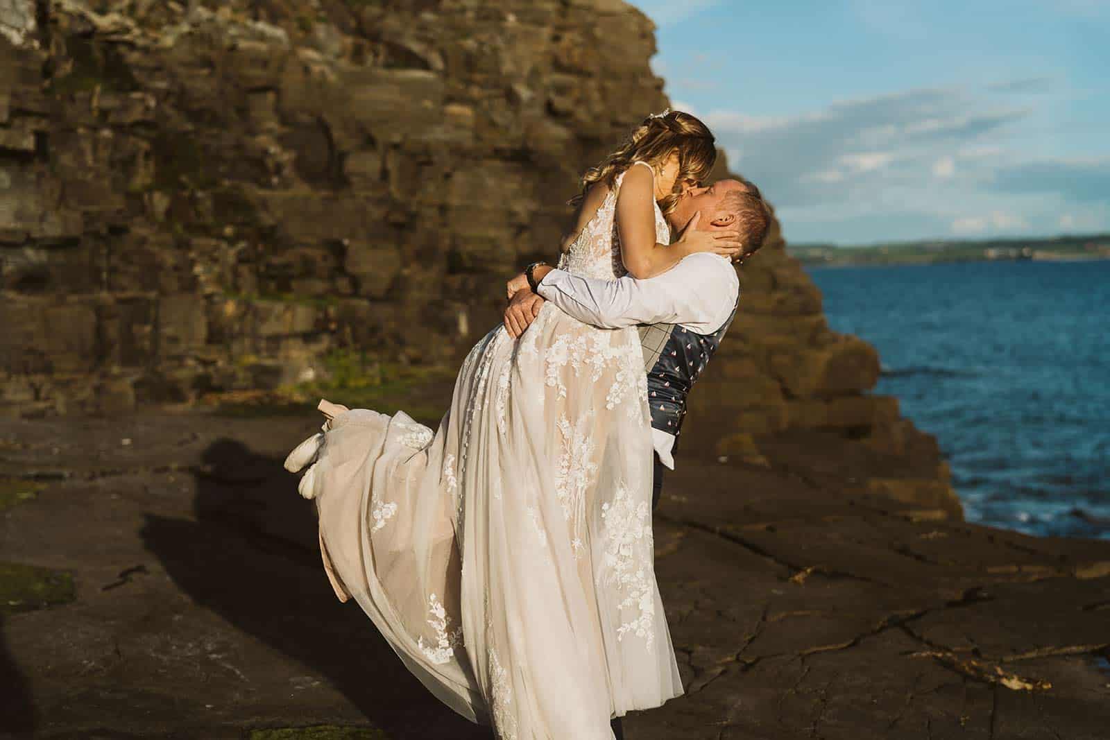 groom picking up bride while eloping in Ireland
