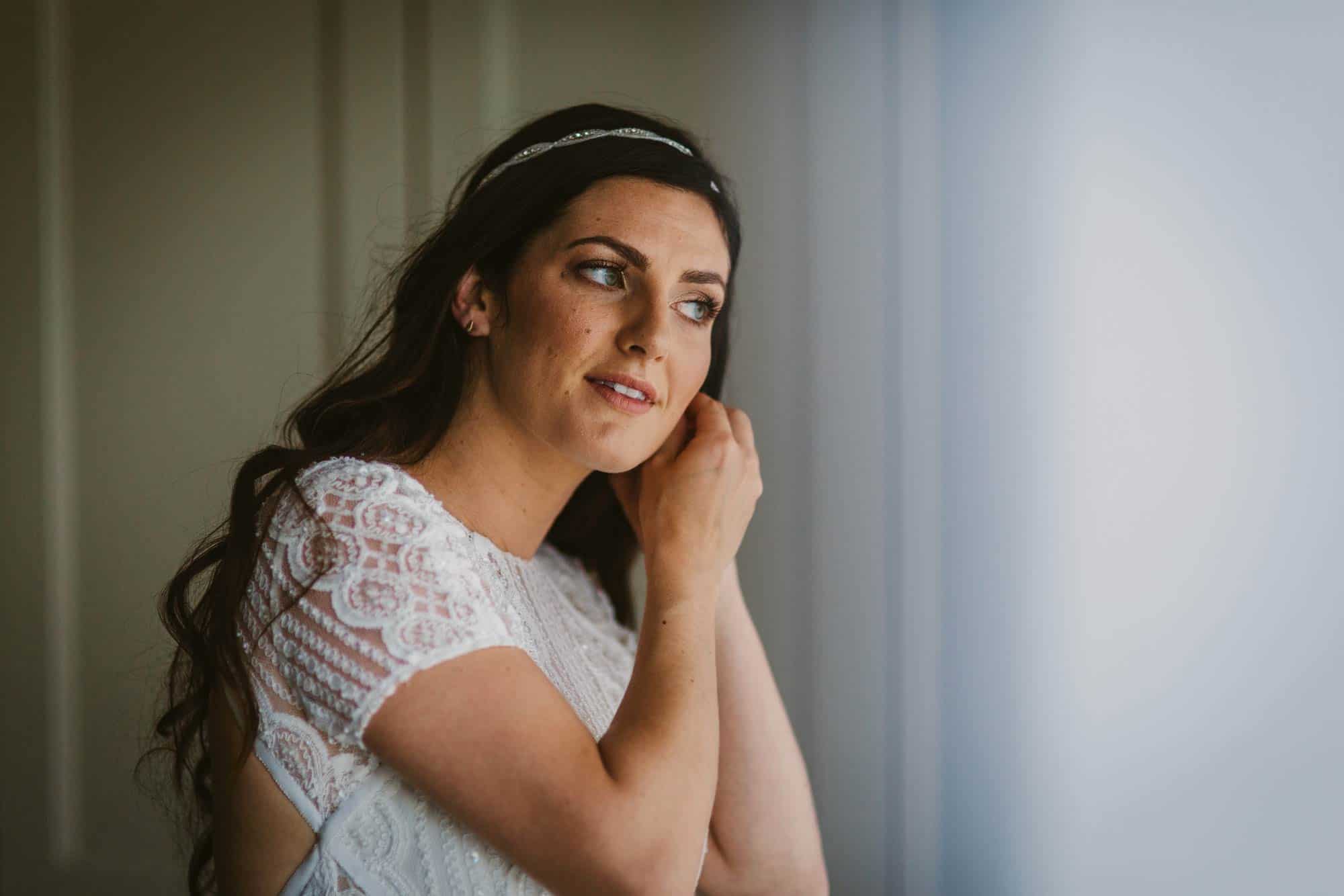 Elopement videographer Ireland, bride putting on earrings